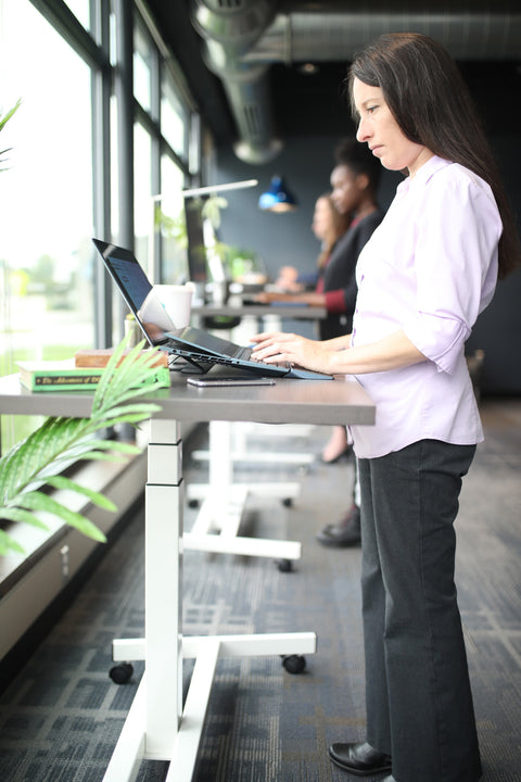 woman working at a sit stand desk, modern office furniture
