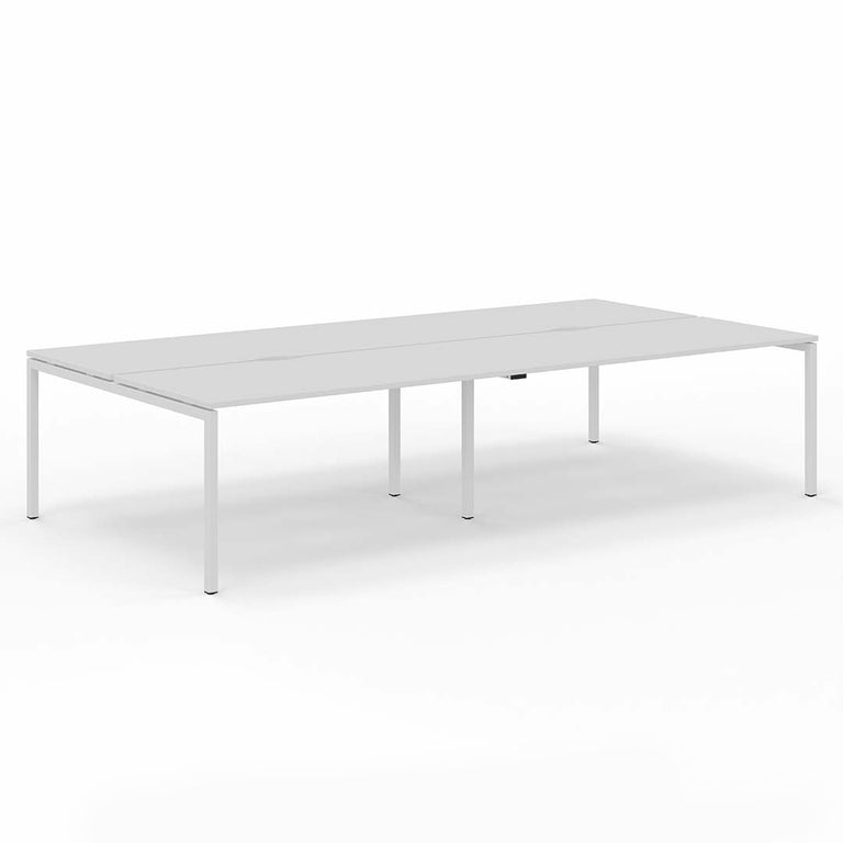 Pod of four bench desks for four office workers in open plan office. White straight legs and white desktop